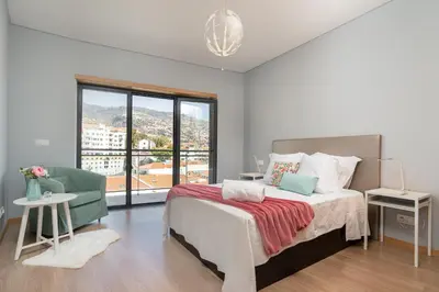 a bedroom with a bed and a chair and a window at Luxurious Apartment Funchal - Casa Valentina - Rent2U, Lda in Funchal