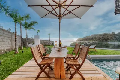 a wooden table with chairs and an umbrella on a patio at CASA 61 by Stay Madeira Island in Ponta do Sol