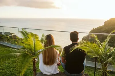 a family sitting on a rock looking at the ocean at CASA 61 by Stay Madeira Island in Ponta do Sol