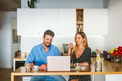 a man and woman sitting at a table with a laptop at CASA 61 by Stay Madeira Island in Ponta do Sol