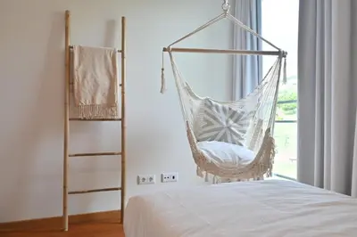 a hanging hammock in a bedroom with a bed at Casa da Julia e Alice, a Home in Madeira in Funchal