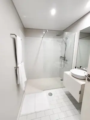 a white bathroom with a shower and a sink at Santa Luzia's Pearl II E - One Bedroom Apartment in Funchal