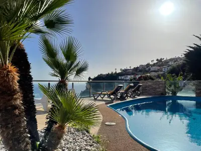 a swimming pool with palm trees and a view of the ocean at Villa Isabela - Car Rental for Free in Caniço