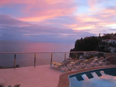 a balcony with chairs and a swimming pool at sunset at Villa Isabela - Car Rental for Free in Caniço