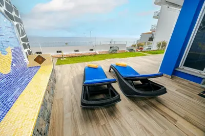 two blue chairs sitting on a balcony with the beach at Casa Maravilha III in Caniço