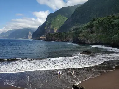 a group of people standing in the water at the beach at Lazy Lizard by the Ocean in Seixal