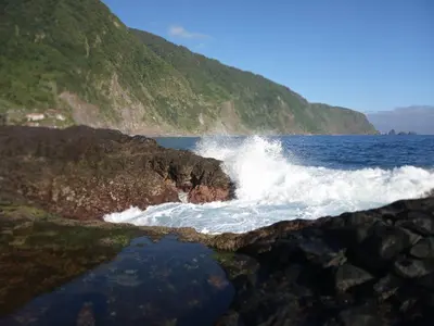 a wave crashing on a rocky shore in the ocean at Lazy Lizard by the Ocean in Seixal