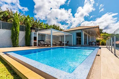 a swimming pool in the backyard of a house at Villa Pinheira IV -Heated swimming pool in Calheta
