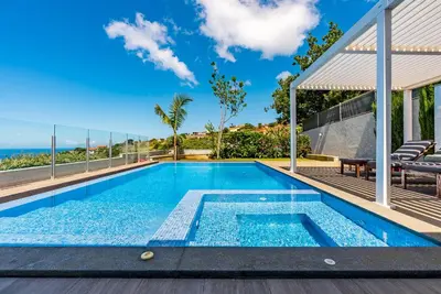 a swimming pool with a view of the ocean from a house at Villa Pinheira IV -Heated swimming pool in Calheta