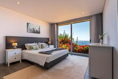 a bedroom with a large bed and a large window at Villa Pinheira IV -Heated swimming pool in Calheta