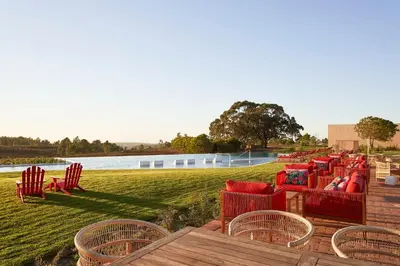 a row of chairs on a deck next to a body of water at Praia do Canal Nature Retreat - Small Luxury Hotels of the World in Aljezur