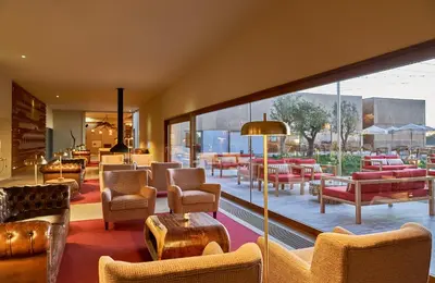 a lobby with chairs and tables and windows at Praia do Canal Nature Retreat - Small Luxury Hotels of the World in Aljezur