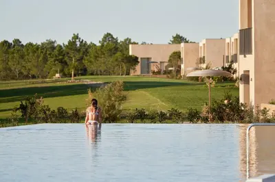 a woman standing in the water in a swimming pool at Praia do Canal Nature Retreat - Small Luxury Hotels of the World in Aljezur