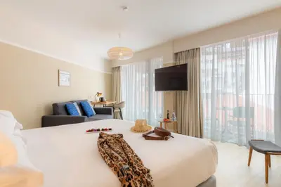 a hotel room with a large white bed and a couch at Pestana Fisherman Village in Câmara de Lobos