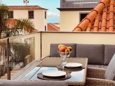 a glass table with a bowl of fruit on a balcony at Living Funchal Apartments in Funchal