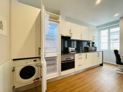 a kitchen with white cabinets and a washer and dryer at Living Funchal Apartments in Funchal