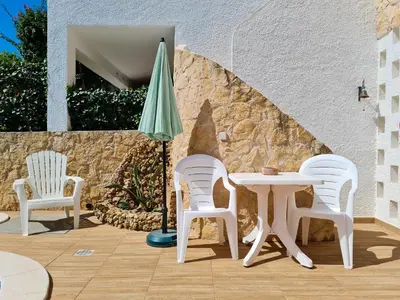 three white chairs and a table and an umbrella at REFÚGIO DO CARANGUEJO - Praia da Luz - WiFi, Private Pool & BBQ in Luz