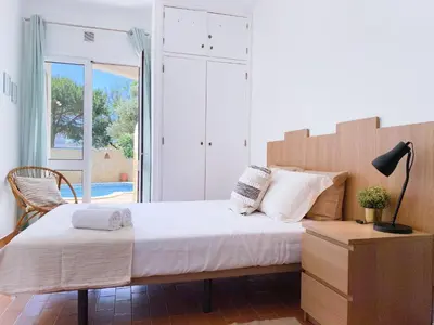 a bedroom with a large bed and a chair at REFÚGIO DO CARANGUEJO - Praia da Luz - WiFi, Private Pool & BBQ in Luz