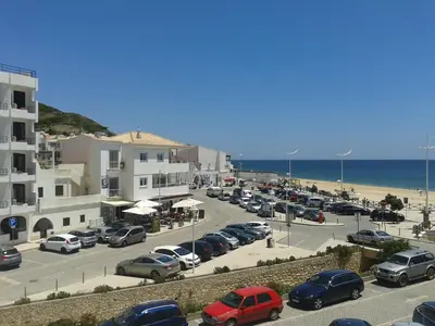 a parking lot with cars parked next to the beach at Salema Beach Apartment in Salema