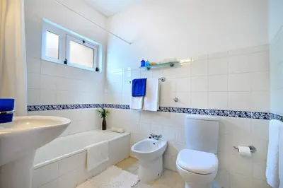 a white bathroom with a toilet and a sink at Villa Cinco by Villa Plus in Luz