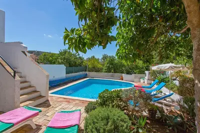a swimming pool with lounge chairs next to a house at Villa Cinco by Villa Plus in Luz