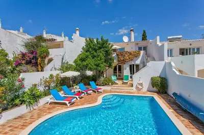 a villa with a swimming pool with chairs and a house at Villa Cinco by Villa Plus in Luz