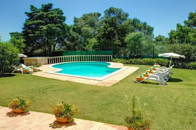 a pool in a yard with chairs and an umbrella at Villa Sounia by Villa Plus in Lagos