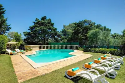 a swimming pool with lounge chairs and a group at Villa Sounia by Villa Plus in Lagos