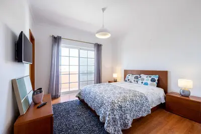 a bedroom with a bed and a large window at Sweet Home Sagres in Sagres