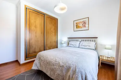 a bedroom with a bed and a wooden cabinet at Sweet Home Sagres in Sagres