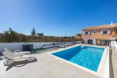 a swimming pool with lounge chairs next to a house at Sweet Home Sagres in Sagres