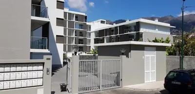a white apartment building with a gate and a car at 1 Bed Apartment Sleeps 4 with Pool in Funchal