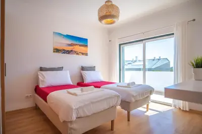 a bedroom with two beds and a large window at Kichershome in Sagres