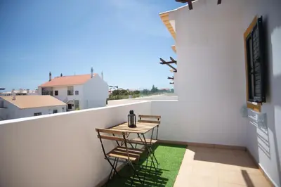 a balcony with a table and chairs on a white wall at Kichershome in Sagres