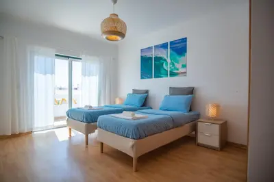 a bedroom with two beds with blue pillows at Kichershome in Sagres