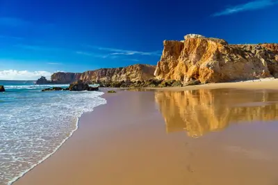 a sandy beach with rocks and the ocean at Kichershome in Sagres