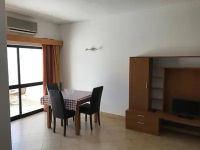a dining room with a table and chairs and a television at Magnólia Mar Senses in Lagos