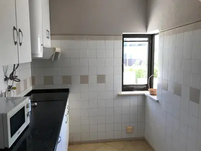 a kitchen with a window and a white tiled wall at Magnólia Mar Senses in Lagos