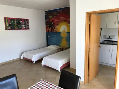 a room with two beds and a kitchen with a painting at Magnólia Mar Senses in Lagos
