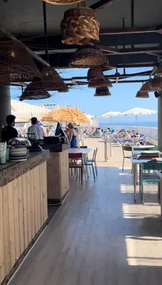 a beach bar with people sitting at tables and umbrellas at Magnólia Mar Senses in Lagos