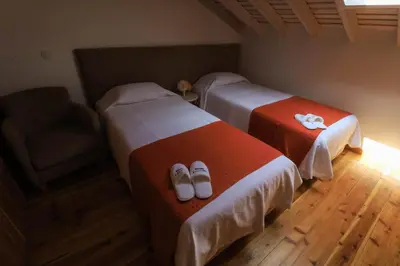 a room with two beds and a chair and shoes at QUINTA DO FALCÃO in Almagreira