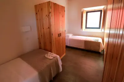 a room with two beds and a cabinet and a window at QUINTA DO FALCÃO in Almagreira