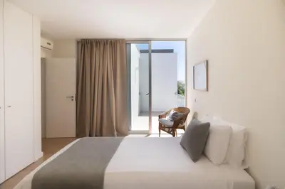 a bedroom with a large white bed and a chair at Blue Villa H - Sagres - 10 min walk to the beach in Sagres