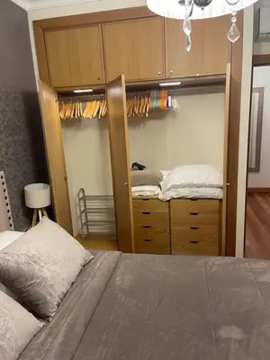 a bedroom with a bed and a wooden closet at Ajuda Paradise apartment with pool and private parking in Funchal