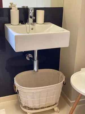 a bathroom with a sink and a basket under it at Bordal Houses Casa da Areia in Porto Santo