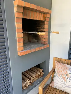 a brick oven in a living room with a wooden chair at Bordal Houses Casa da Areia in Porto Santo