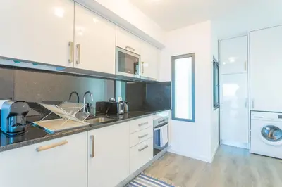 a kitchen with white cabinets and a washer and dryer at FLH Fantastic Ocean View with Balcony in Santa Cruz
