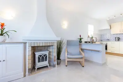 a white kitchen with a chair and a fireplace at Apartamento Salema 33 in Salema