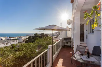 a balcony with an umbrella and a view of the ocean at Apartamento Salema 33 in Salema