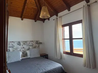 a bedroom with a bed and a large window at Cozy Sea View House Fajã da Ovelha in Calheta